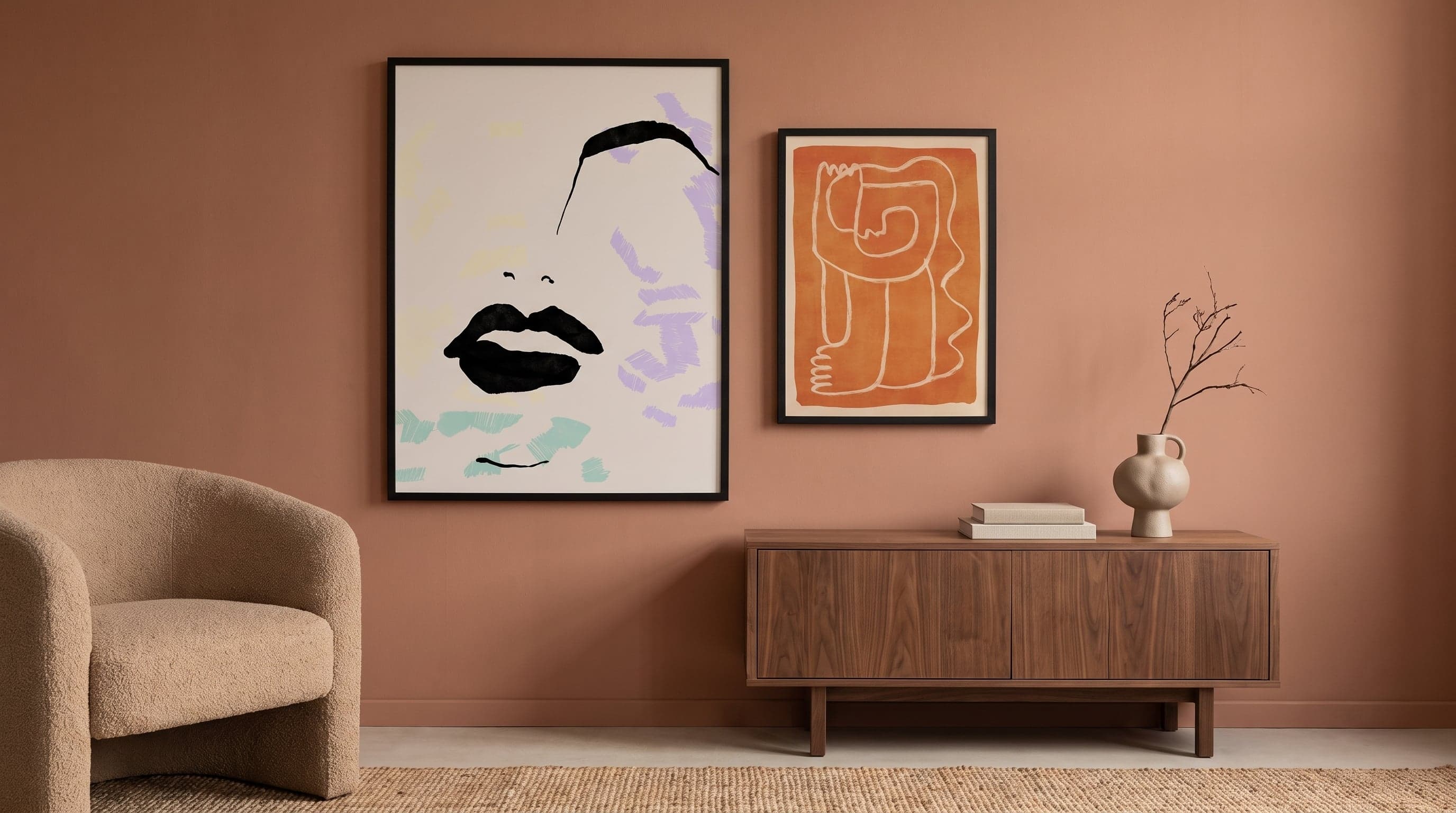 Varmt minimalistiskt vardagsrum med två grafiska porträttposters i olika storlekar på terrakottavägg